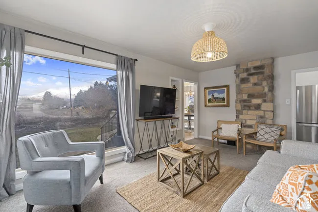 Spacious living area featuring a large picture window, stone accent wall, and a woven pendant light fixture