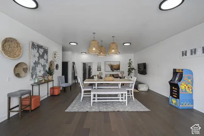 Open-concept living space with dark wood-finish flooring, recessed ceiling lighting, and woven pendant light fixtures