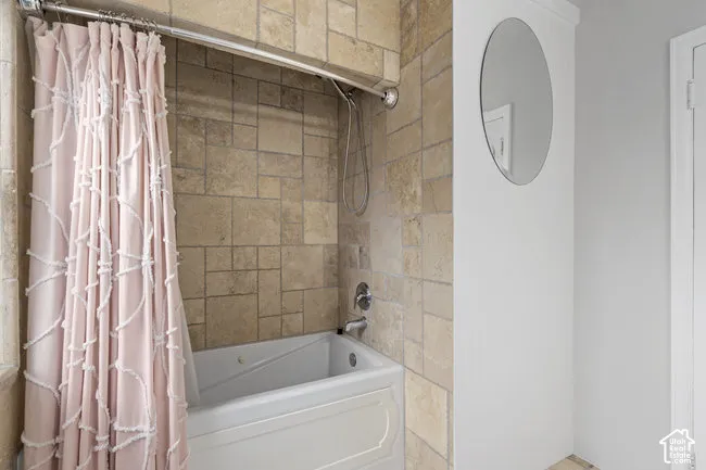 Bathtub with chrome fixtures and light-toned tile surround