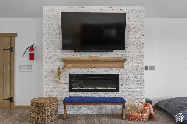 Whitewashed brick fireplace with a wood mantle, an inset electric fireplace, and a light wood paneled door