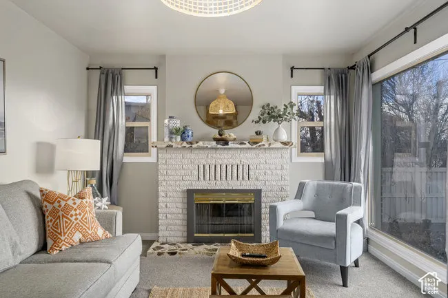 Living area featuring a painted brick fireplace, a ceiling light fixture, a large sliding glass door, and two windows with wood-finish trim