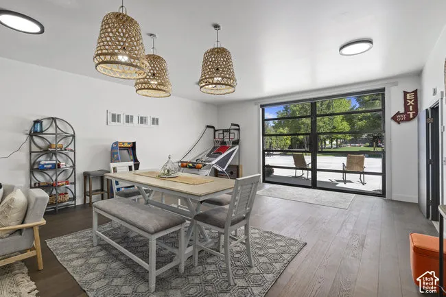 Recessed ceiling lighting, three woven pendant light fixtures, wood-finish flooring, and a full-light glass overhead door