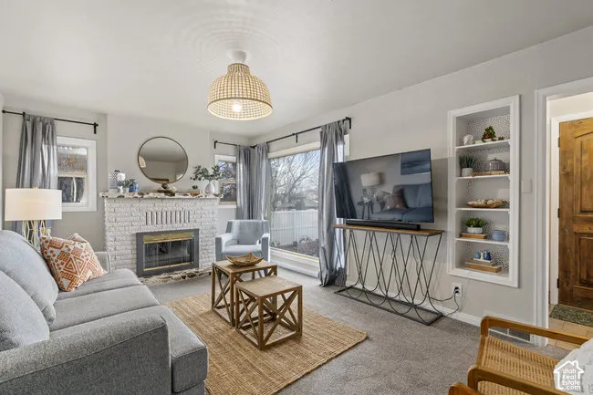 Living area featuring a painted brick fireplace, a built-in shelving unit, and multiple windows