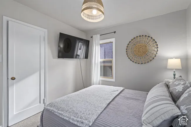 Wall-mounted television, neutral wall color, window with white trim, door with brass hardware, and a ceiling-mounted light fixture