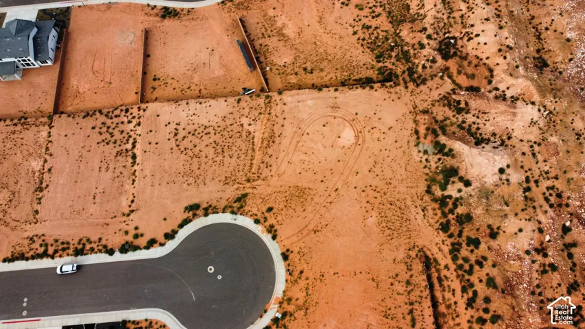 Vacant parcel of land featuring desert topography, native vegetation, and established asphalt cul-de-sac infrastructure