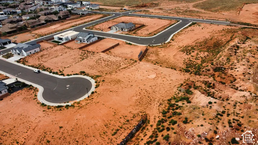 Aerial perspective of undeveloped desert terrain featuring paved cul-de-sac infrastructure and tiered retaining walls