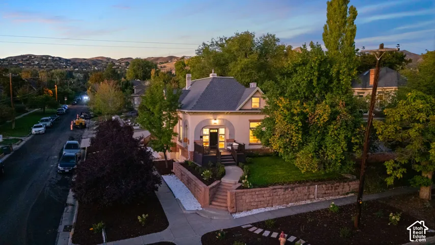 Single-story residence featuring a steep hipped roof, covered arched entryway, raised porch, and a tiered stone retaining wall