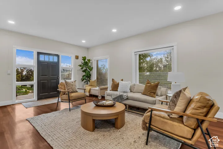 Living area featuring wood-finish flooring, recessed lighting, neutral walls, and large windows with horizontal blinds