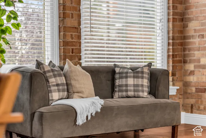 Exposed brick walls, wood-finish flooring, and large windows featuring horizontal blinds