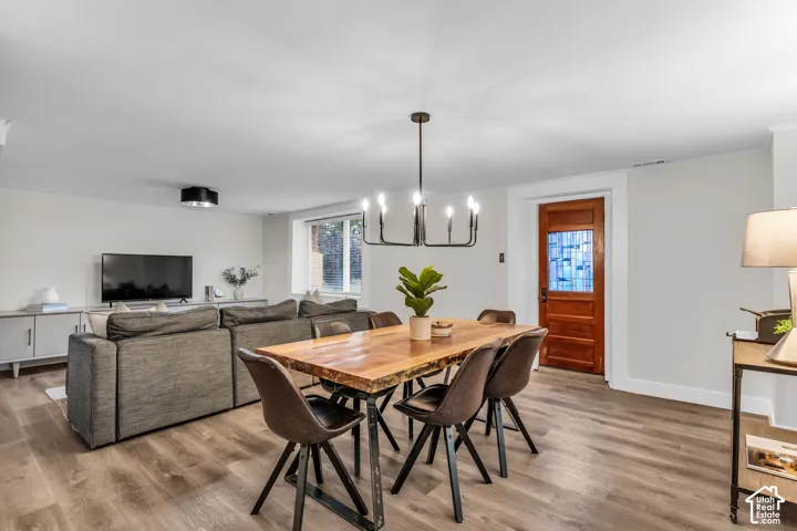 Open-concept living space featuring wood-finish flooring, a multi-arm modern chandelier, a built-in cabinet console, and a solid wood entry door with decorative glass paneling