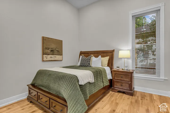 Room featuring wood-finish flooring, a tall double-hung window with white casing, and neutral wall paint