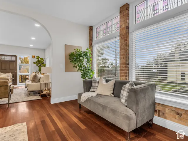 Interior space featuring wood-finish flooring, exposed brick structural elements, and large-scale windows with decorative stained glass transom panels, separated by an arched architectural opening