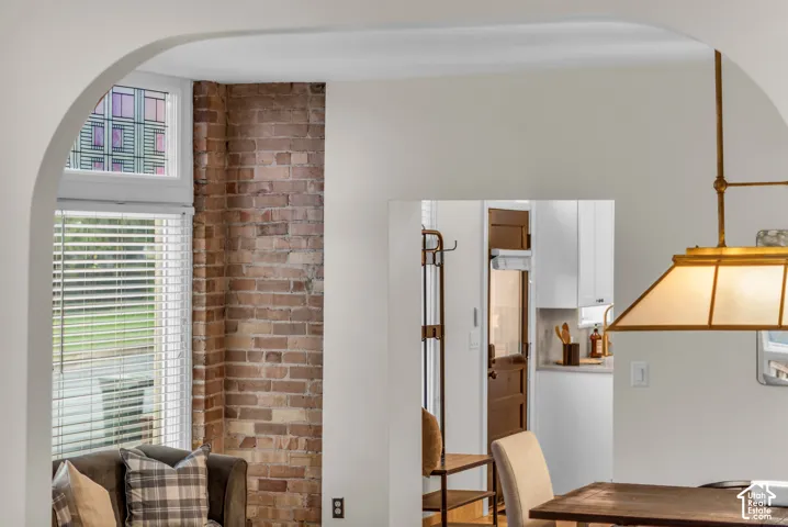 Arched doorway framing an exposed brick pillar, multi-pane transom window, and brass-finish pendant lighting
