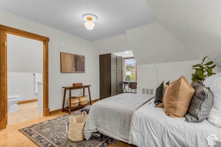 Vaulted ceilings, wood-finish flooring, natural wood door casing, and a vintage-style flush-mount light fixture