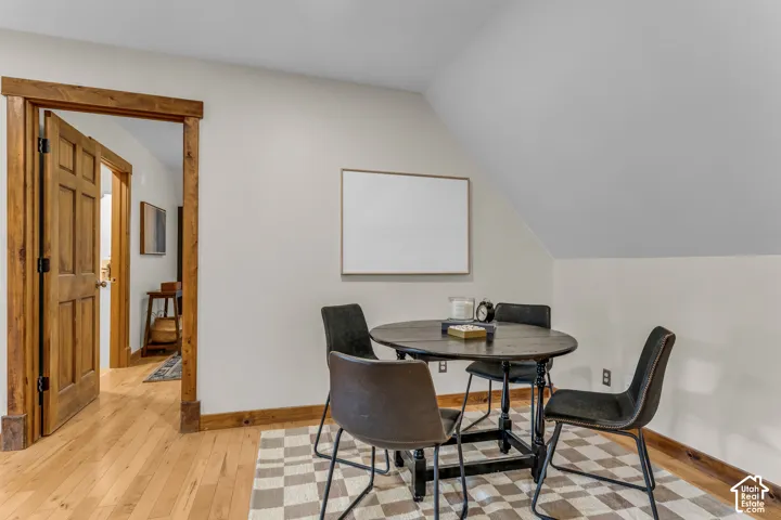 Interior room featuring wood-finish flooring, stained wood door casing, and architectural sloped ceiling