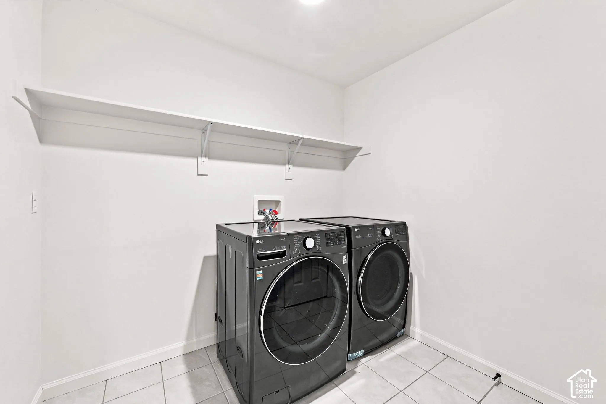 Laundry area featuring tile flooring and a wall-mounted shelving unit