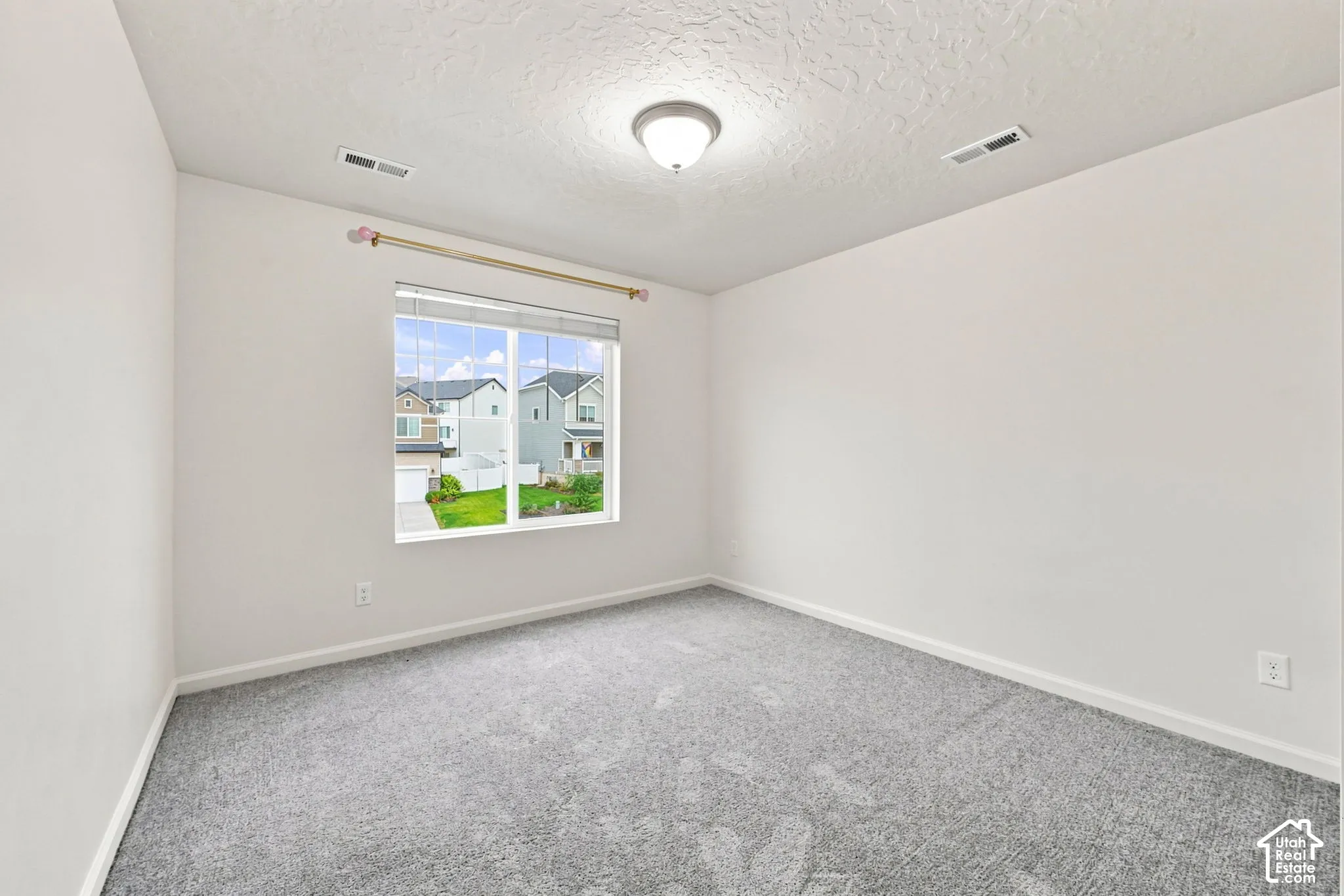 Neutral-toned room featuring grey wall-to-wall carpeting, a flush-mount ceiling light fixture, and a large window with white blinds