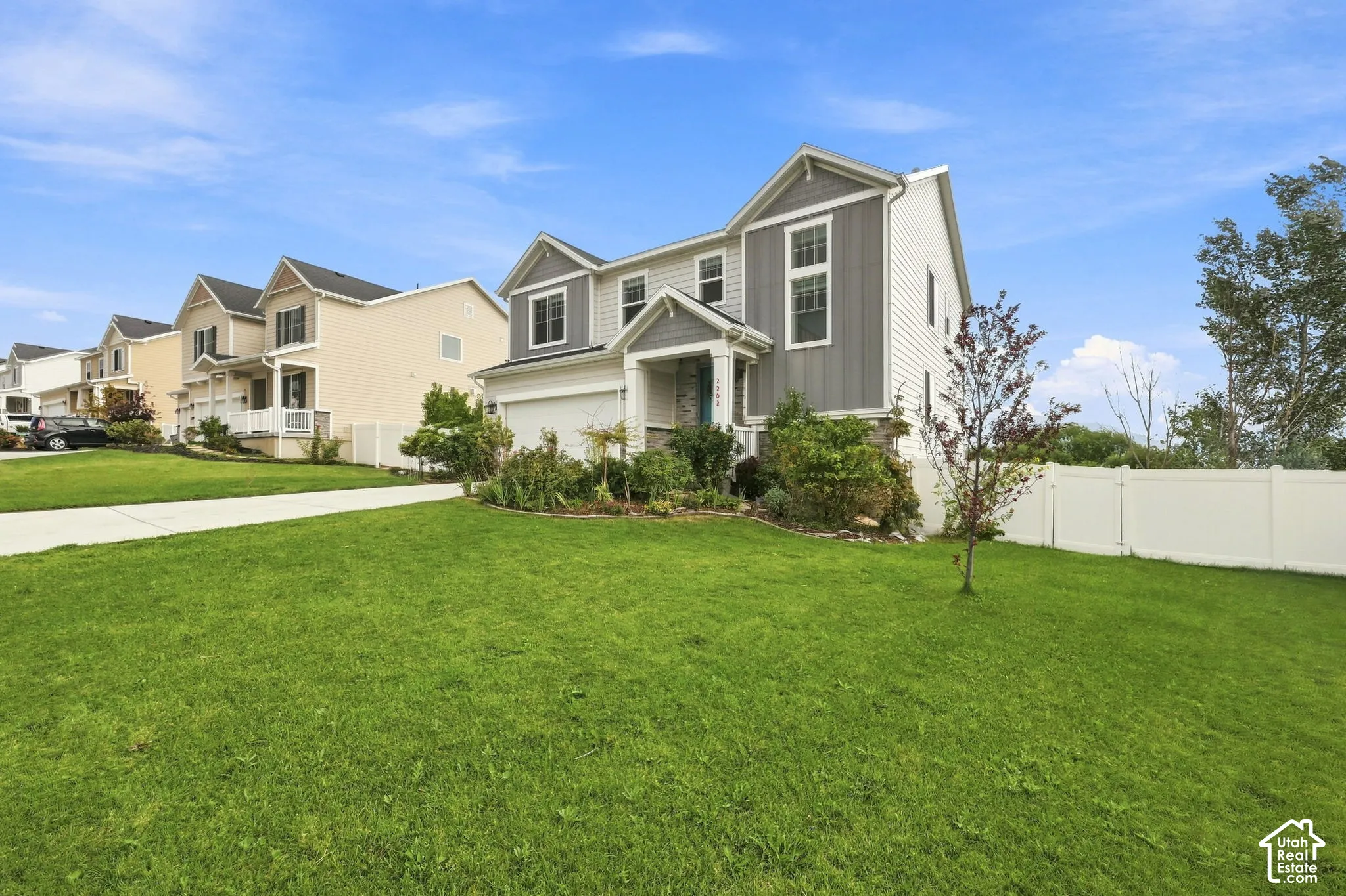 Two-story residence featuring a mixed-material exterior of horizontal lap siding and vertical board-and-batten accents, a stone veneer entryway, a two-car garage, and a fenced yard
