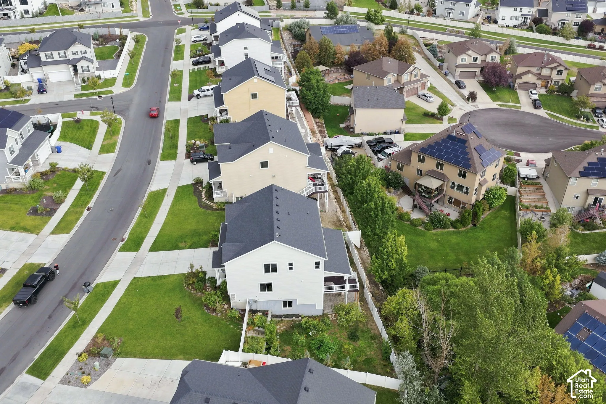 Aerial perspective of a suburban neighborhood featuring paved streets, sidewalk grid, residential homes with asphalt shingle roofs, and established greenery