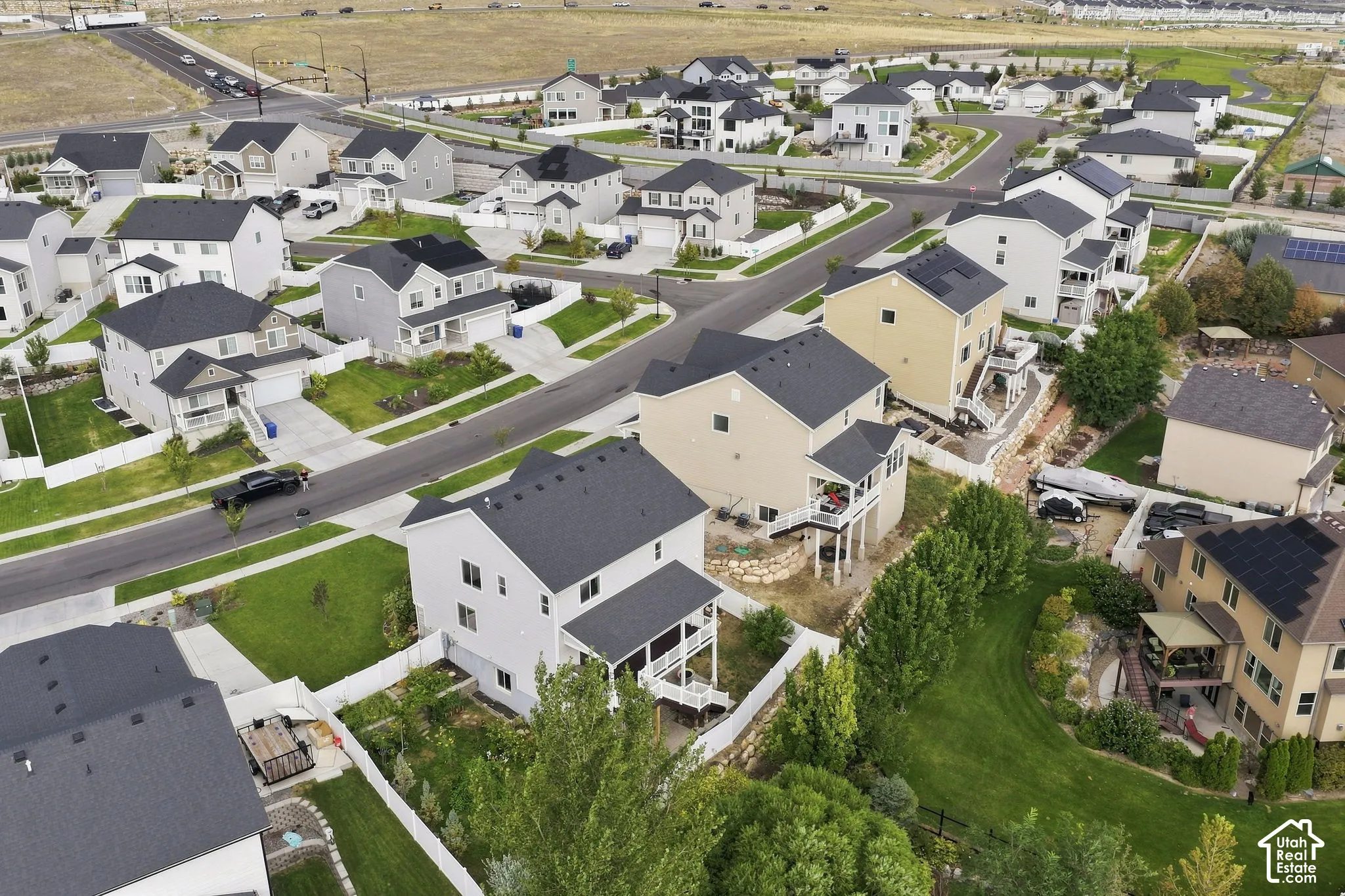 Aerial perspective of a planned community featuring multi-story residences with asphalt shingle roofing, concrete driveways, and integrated rear deck structures