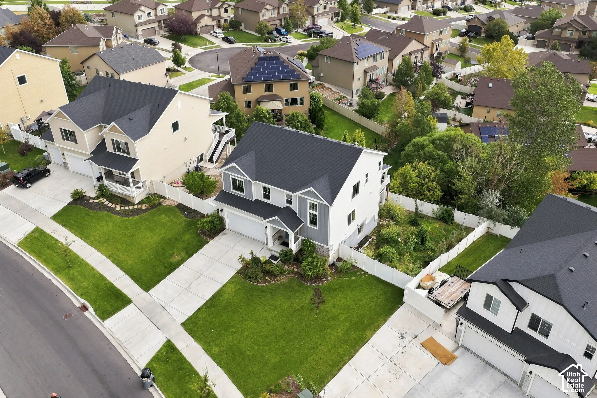 Two-story residence featuring a concrete driveway, attached garage, gabled roofline, mixed-material siding, and enclosed perimeter fencing