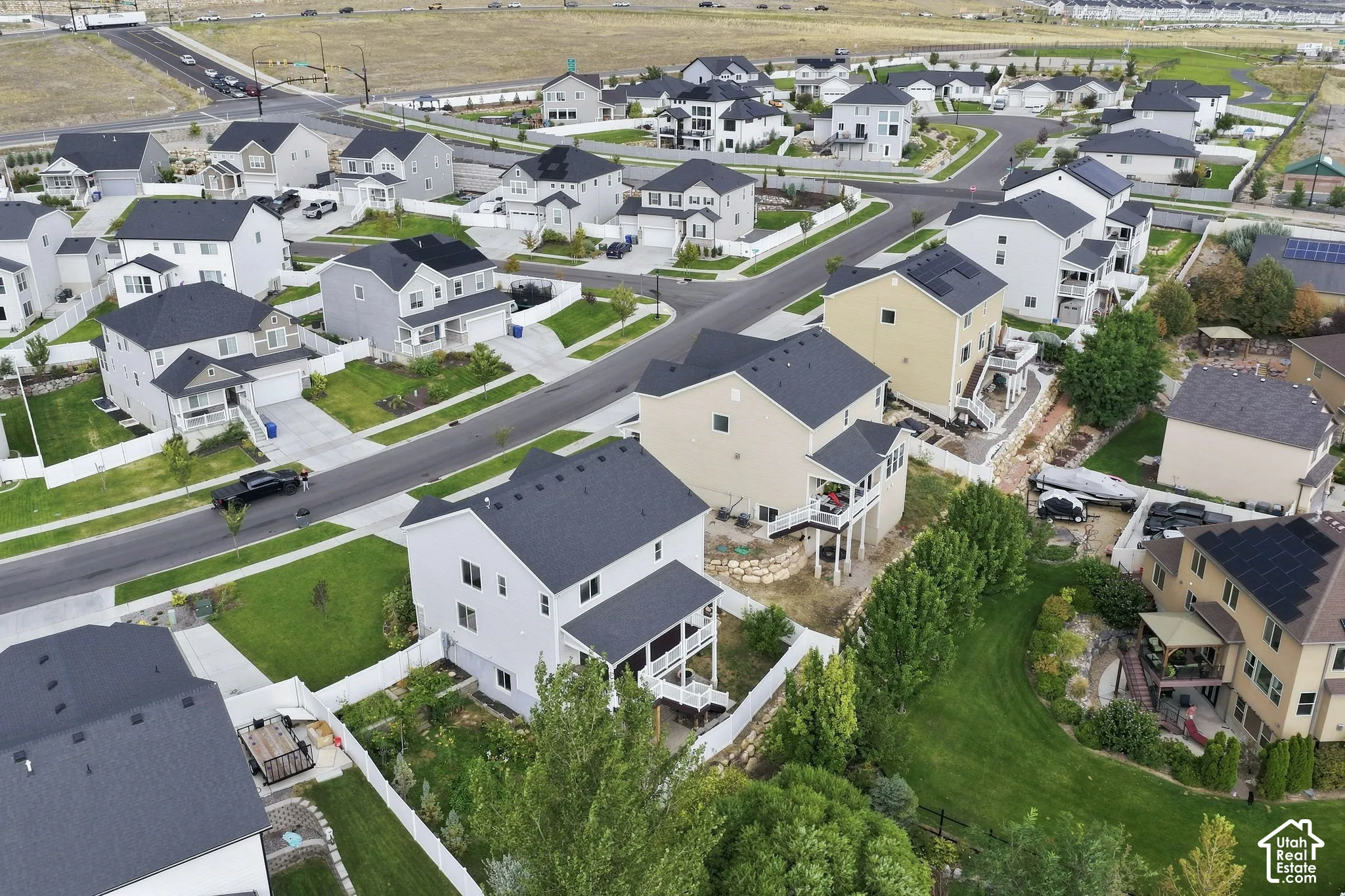 Aerial perspective featuring multi-story residential structures with pitched roofing, elevated decks, attached garages, and fenced perimeter yards
