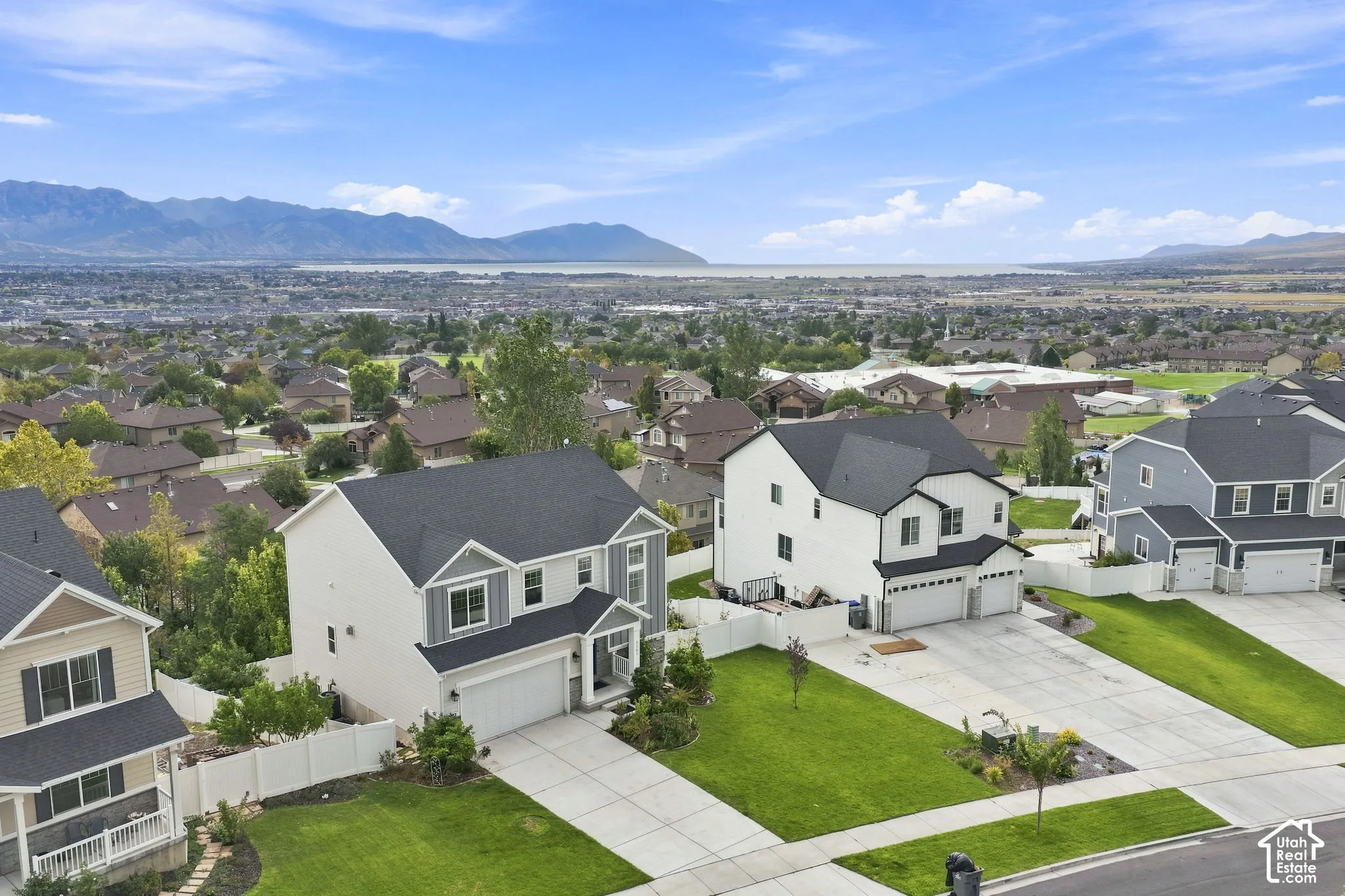 Aerial perspective featuring multi-story residential properties with asphalt shingle roofing, attached two-car garages, concrete driveways, and expansive mountain and valley scenery