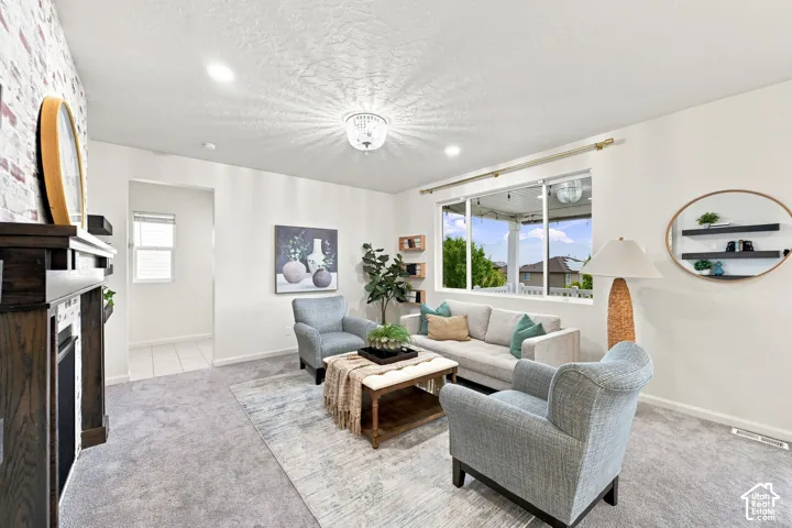Living area featuring a fireplace with a textured brick-style surround, dark wood-finish mantel, recessed lighting, and a multi-light flush mount ceiling fixture