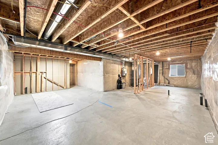 Unfinished lower level featuring exposed wood joist ceilings, concrete flooring, insulated wall segments, and a single window