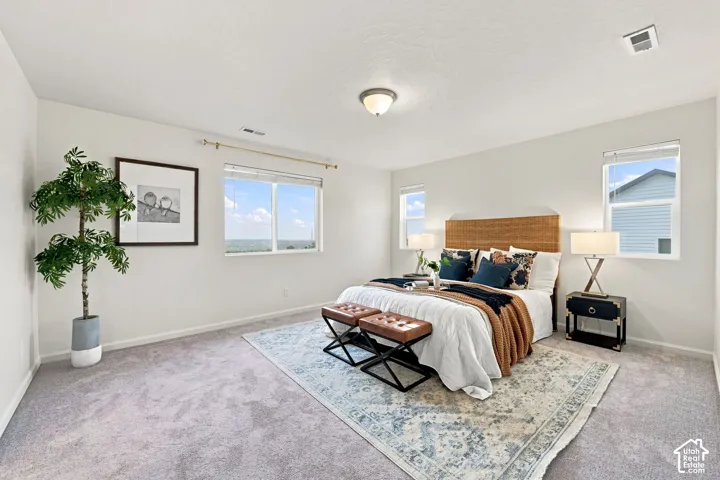 Neutral-toned carpeted flooring, three windows with natural light exposure, and flush-mount ceiling lighting