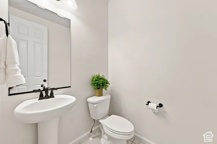 White pedestal sink with a dark metal widespread faucet, large rectangular mirror, and dark metal hardware fixtures
