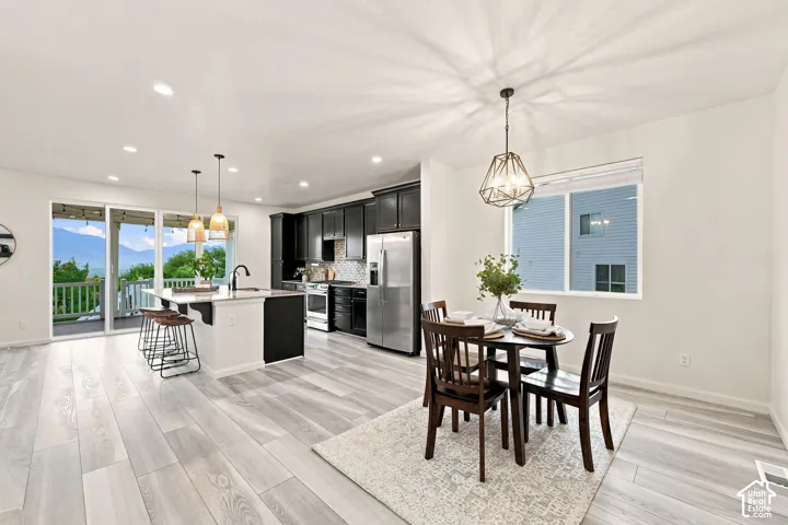 Kitchen featuring dark cabinetry, quartz-topped center island with pendant lighting, stainless steel appliances, and wood-finish flooring