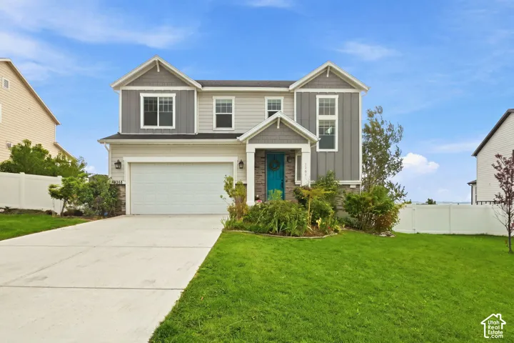 Two-story residence featuring a combination of horizontal lap and vertical board-and-batten siding, stone veneer accents, an attached two-car garage, and a covered front entryway