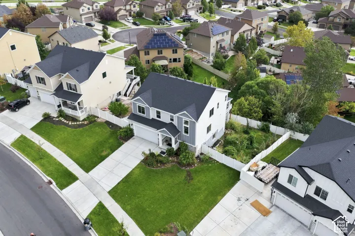 Two-story residence featuring a multi-gable asphalt shingle roof, white vinyl siding, concrete driveway, and enclosed backyard with white privacy fencing