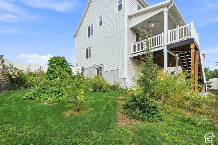 Two-story exterior featuring light-toned horizontal siding, a raised wooden deck with white railing, and a private backyard with established greenery