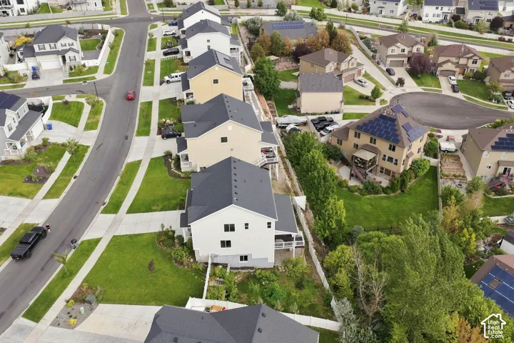 Aerial perspective of a multi-story residential property featuring a shingled roof, light-toned siding, a rear deck, and a fenced backyard
