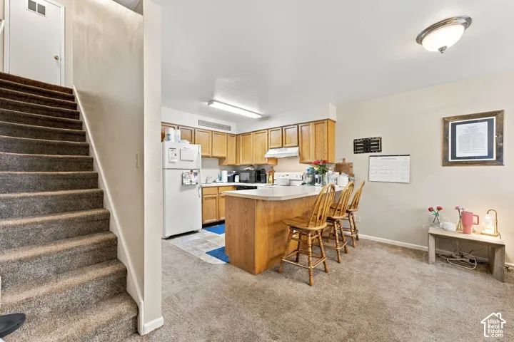 Kitchen featuring wood cabinetry, a breakfast bar, and carpeted flooring