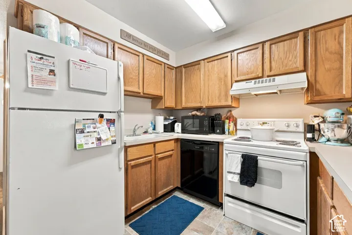 Kitchen featuring wood cabinetry, white appliances, a dishwasher, and a flush-mount overhead light fixture