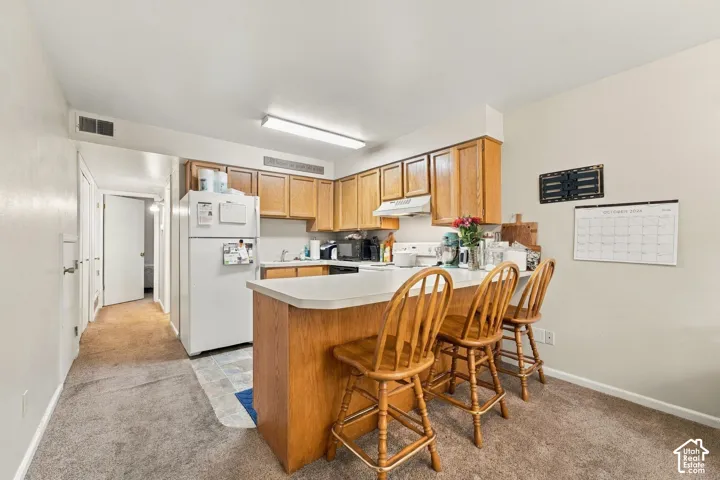 Kitchen featuring wood cabinetry, a peninsula with counter seating, and a mounted range hood
