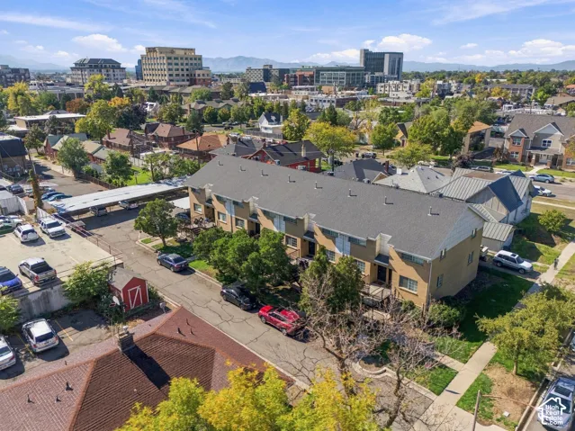 Multi-level residential exterior featuring brick and siding facade, asphalt shingle roofing, private surface parking, and mature landscaping