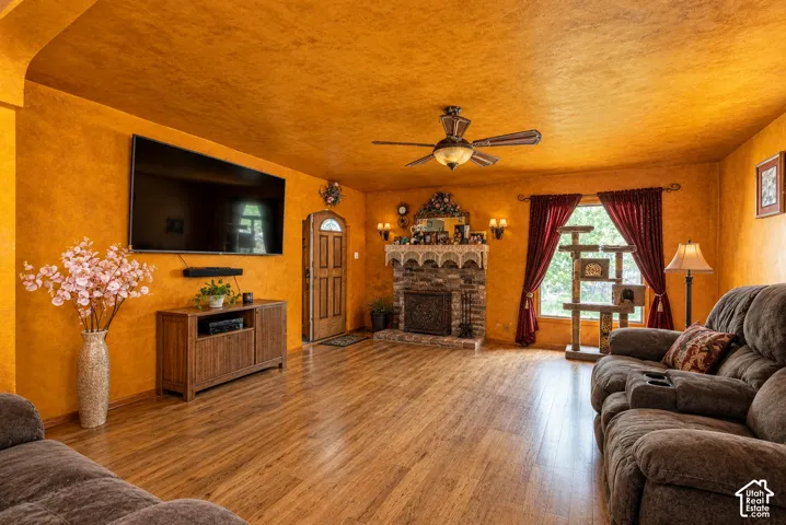 Textured wall finish, wood-finish flooring, masonry fireplace with an arched hearth, and an integrated ceiling fan  (Photo has been virtually decluttered)