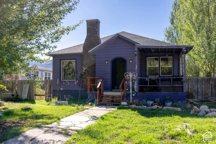 Single-story residence featuring horizontal lap siding, an exterior brick chimney, a covered front porch, and a flagstone walkway