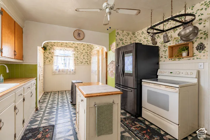 Kitchen featuring a central island with a stone top, white cabinetry, a built-in electric range, a multi-door refrigerator, and patterned tile flooring (Photo has been virtually decluttered)