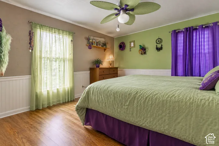 Wood-finish flooring, white wainscoting, and a ceiling fan with integrated light fixture  (Photo has been virtually decluttered)