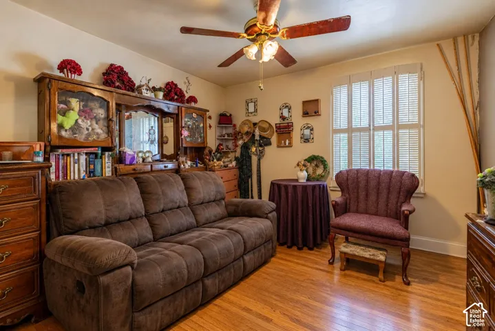 Wood-finish flooring, white plantation shutters, and a central ceiling fan with integrated light fixture  (Photo has been virtually decluttered)