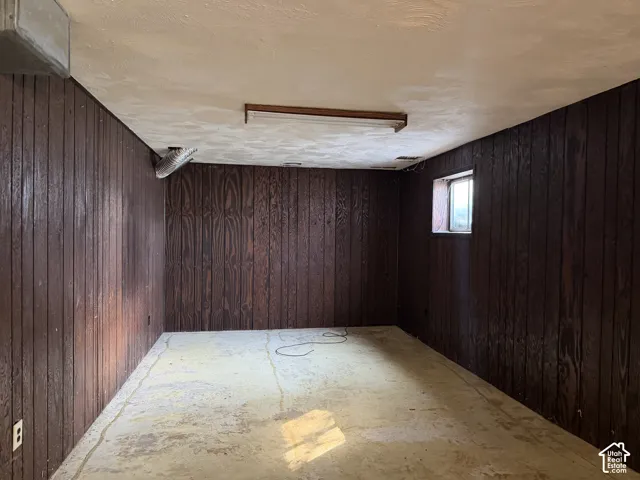 Wood-paneled walls, concrete flooring, and a rectangular window