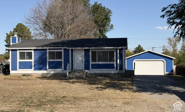 Single-story exterior featuring blue siding, white trim, a concrete driveway, and a detached two-car garage