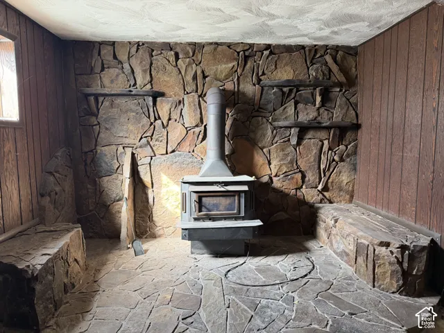 Floor-to-ceiling flagstone hearth featuring a metal wood-burning stove, integrated stone bench seating, and wood paneling