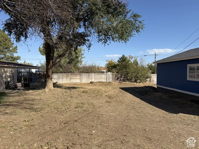 Open yard area featuring wood privacy fencing and mature trees
