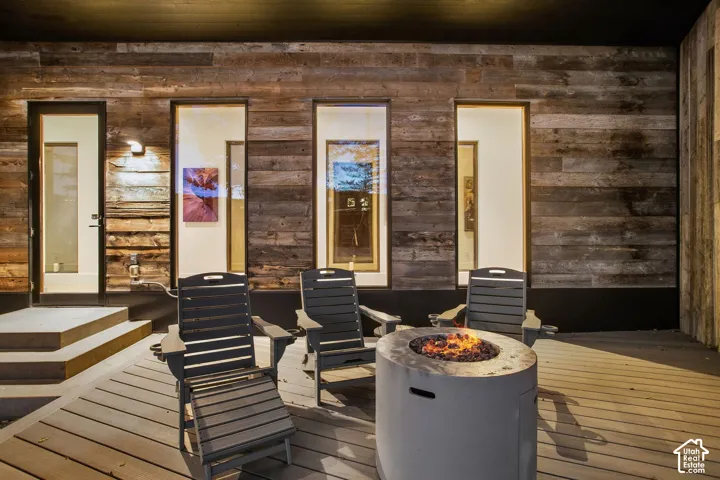 Covered deck featuring horizontal wood-plank siding, full-height windows, and a raised entry platform